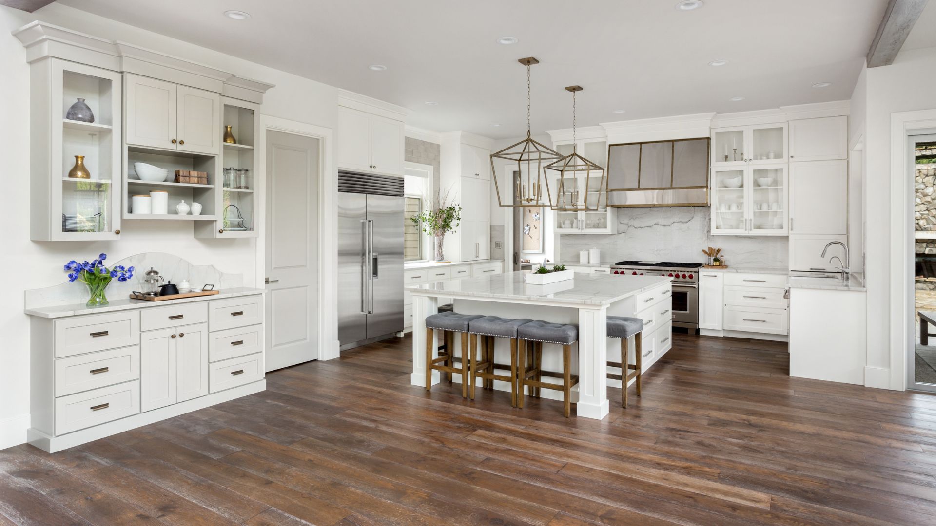 A large kitchen with white cabinets and a wooden floor