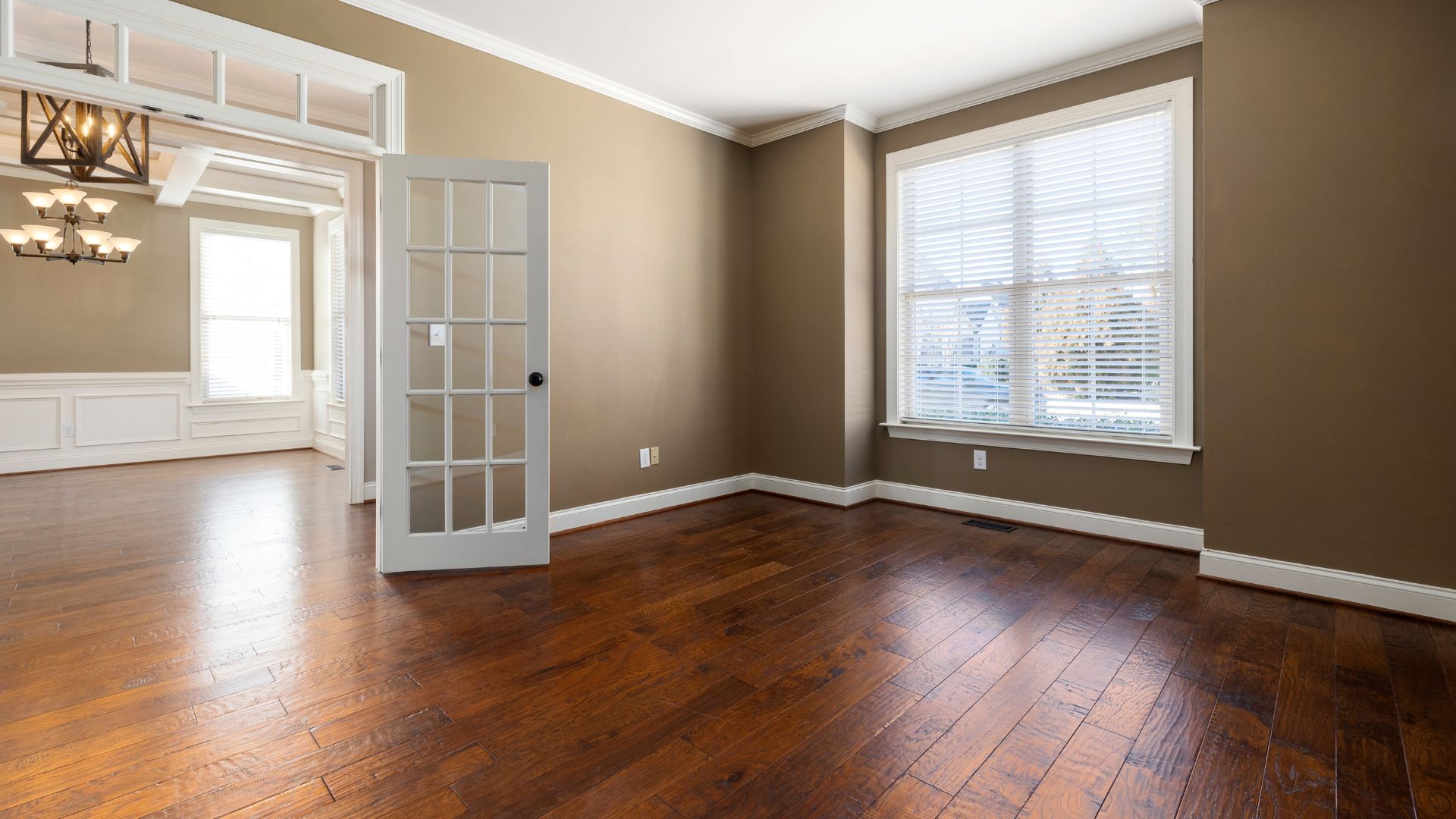 An empty room with hard wood floors and white trim