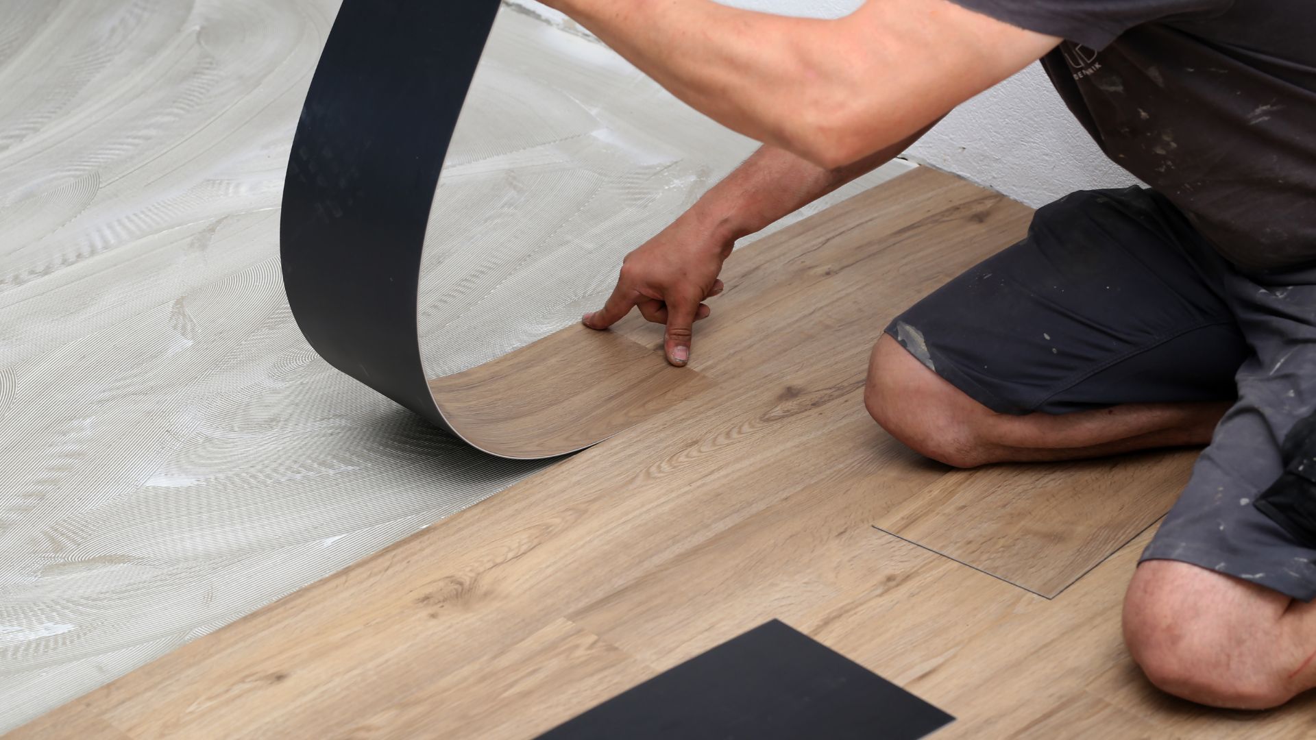 A man working on a wooden floor with a tape